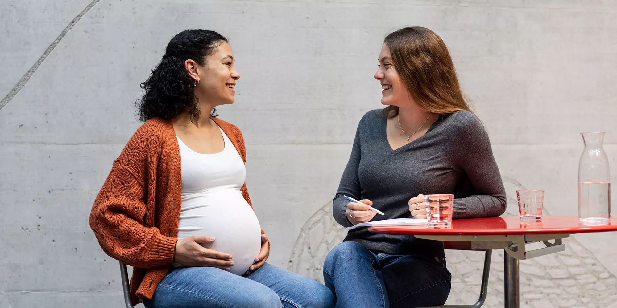 Eine Schwangere und eine Studentin unterhalten sich. 