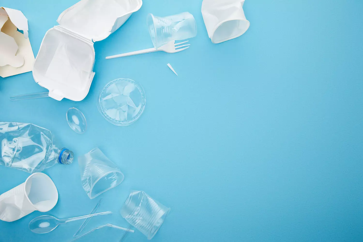 top view of plastic and cardboard rubbish on blue background with copy space