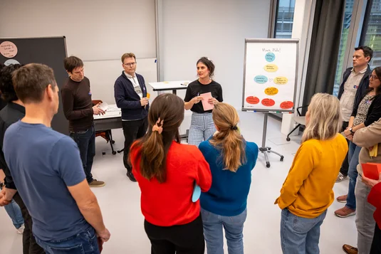 Bild vergrössern: Teilnehmende des Workshops Zivilcourage stehen vor einem Flipchart, auf dem Inputs zum Thema "Helfen in Gefahrensituationen" gesammalt wurden