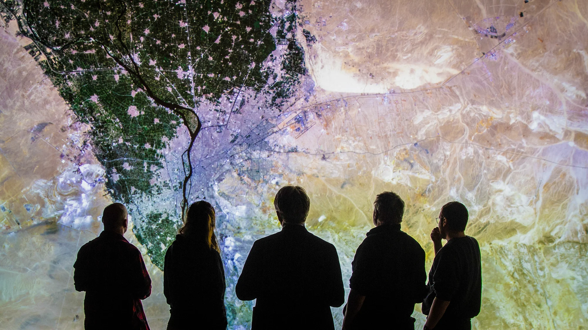 A group of people is looking at a map of a city at the IMMERSE Theater.