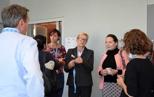 Kaffeepausenraum. Susanne Jekat, Christiane Hohenstein und eine Gruppe Konferenzeilnehmende unterhalten sich während der Kaffeepause.