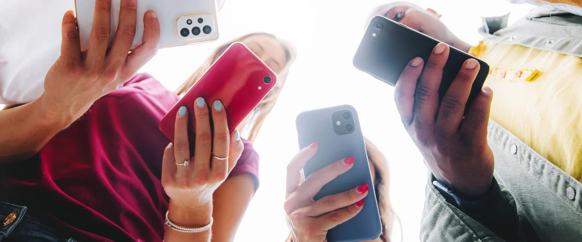 Jugendliche im Kreis halten ihr Smartphone