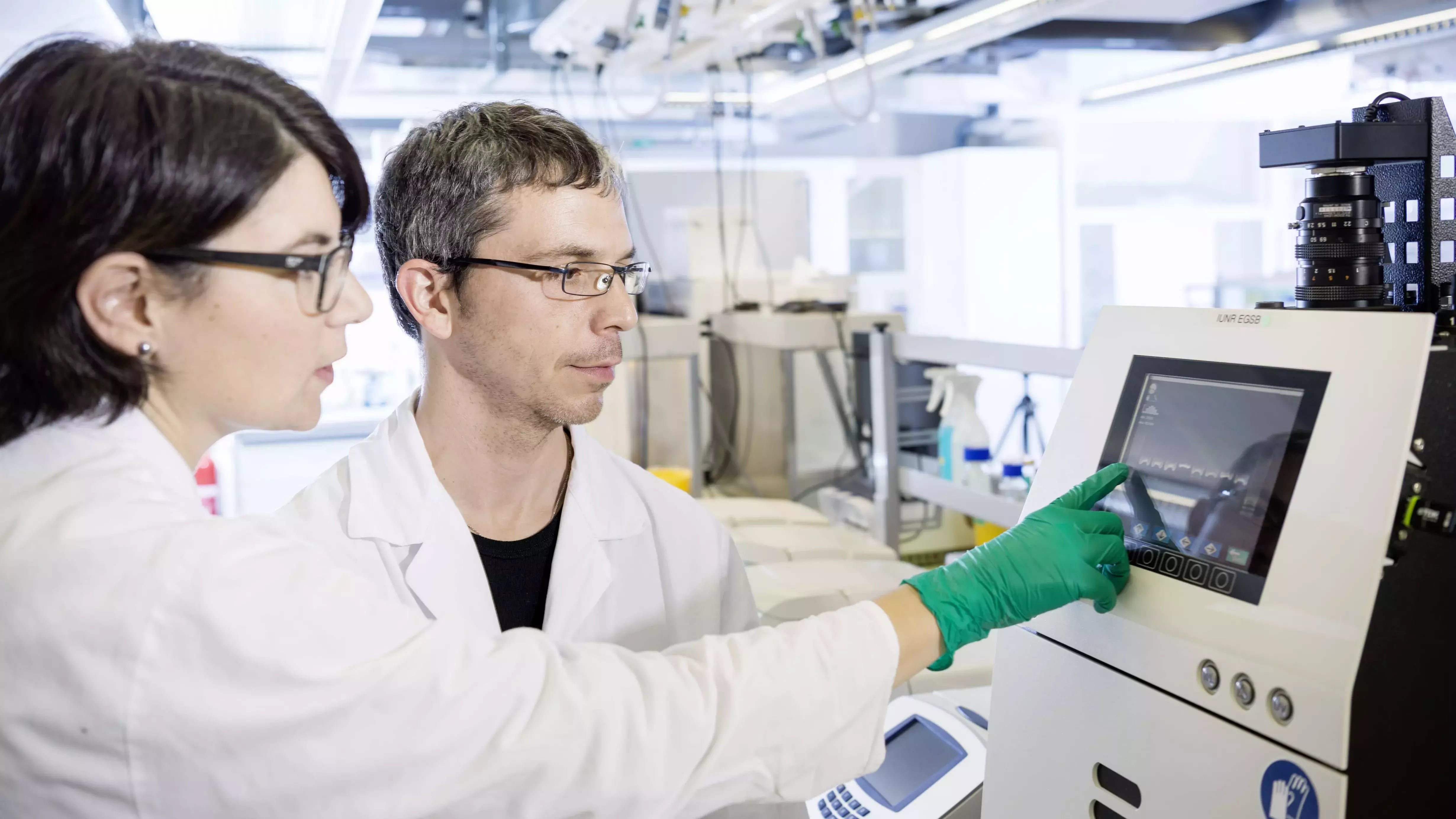 Zwei Mitarbeitende der ZHAW stehen im Labor und deuten auf einem Monitor.