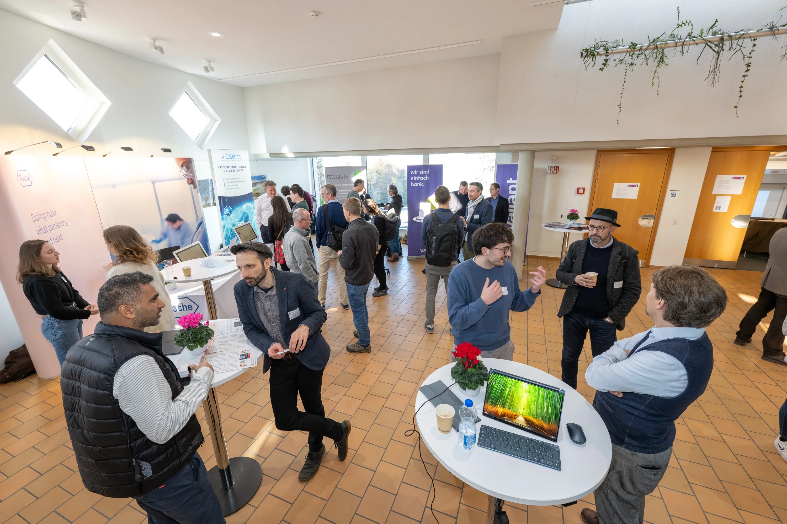 Teillnehmende die um Stehtische stehen und miteinander reden