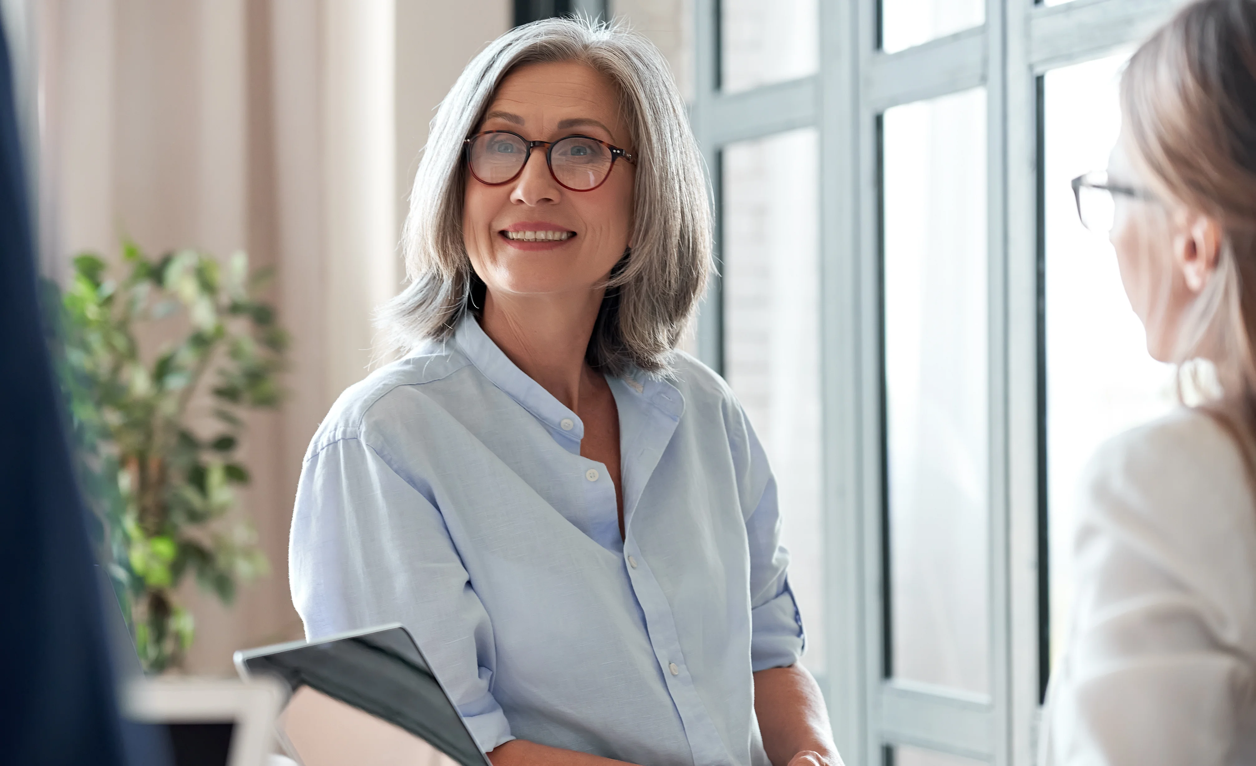 Smiling older female coach teacher communicating with students or interns