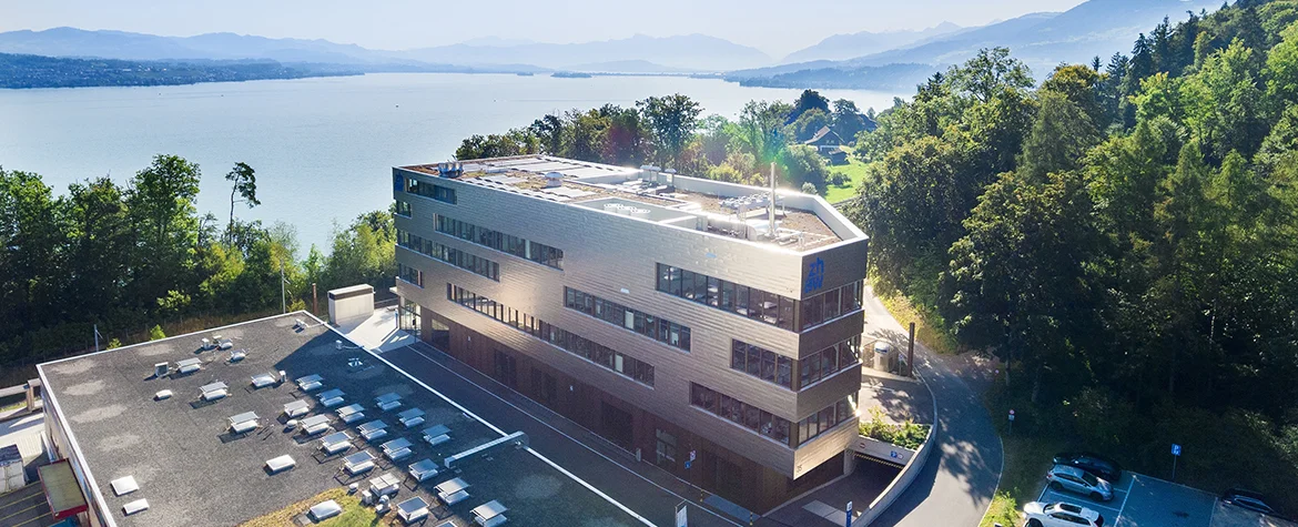 Modernes ZHAW-Gebäude RD in Wädenswil mit Blick auf den Zürichsee und die Berge im Hintergrund.