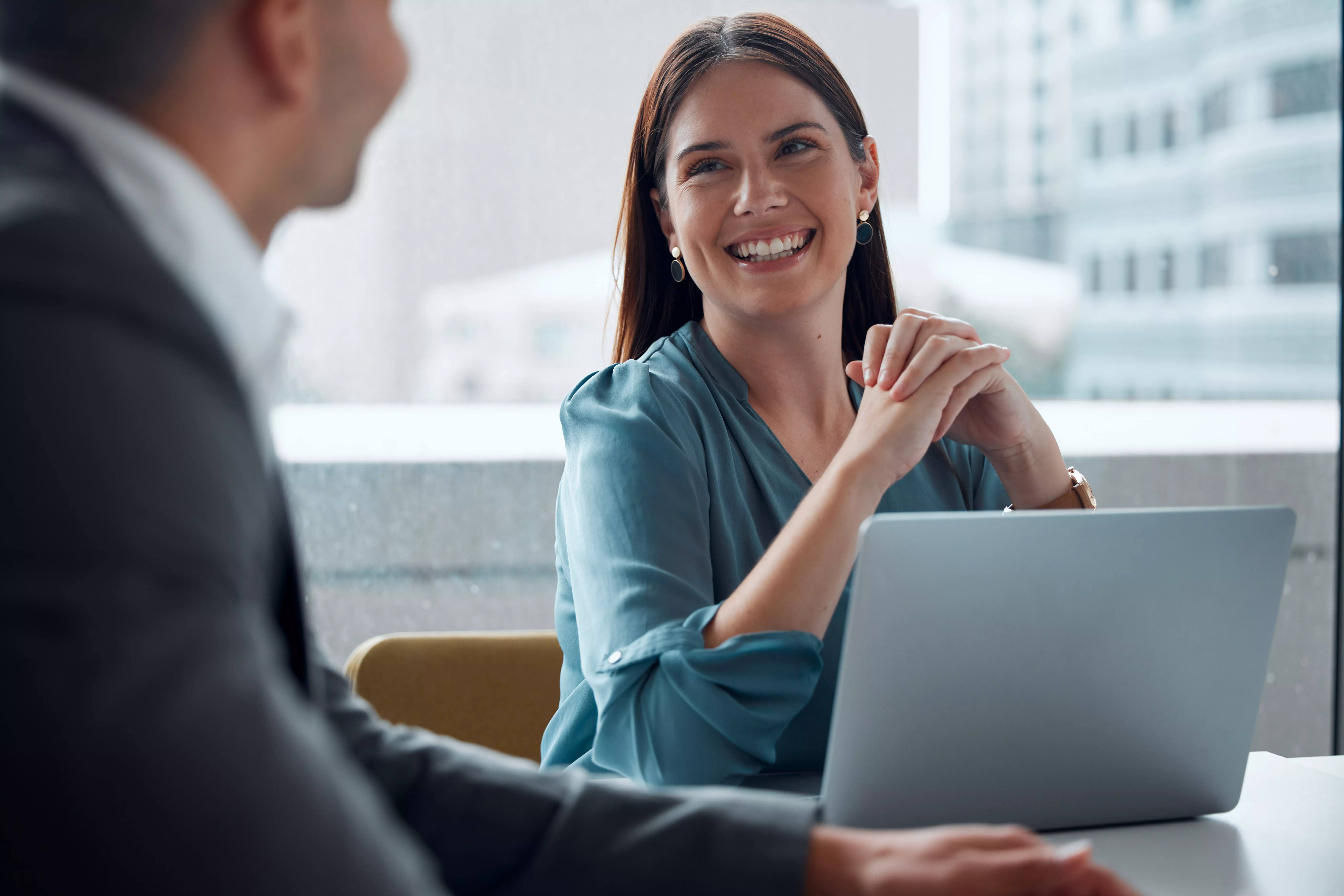 Business meeting, woman and happy with laptop, working in company office, building or teamwork discussion. Female employee, manager or conversation with executive, ceo or feedback from boss