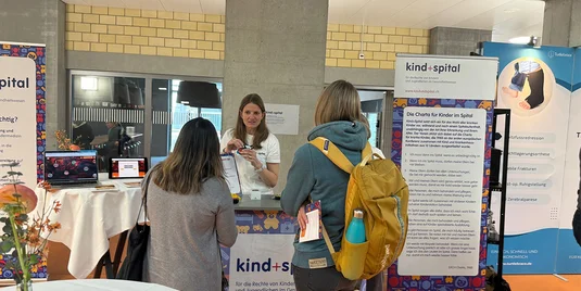 Bild vergrössern: drei Personen am Stand von Kind + Spital
