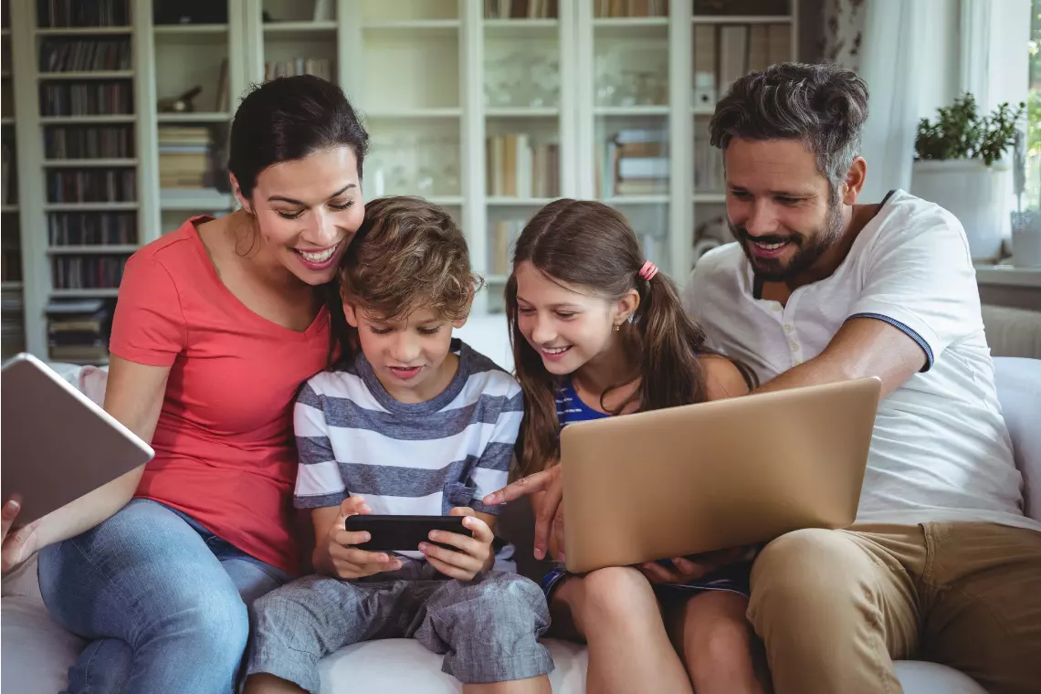 Eltern mit Kindern schauen sich gemeinsam auf dem Smarthpone etwas an.