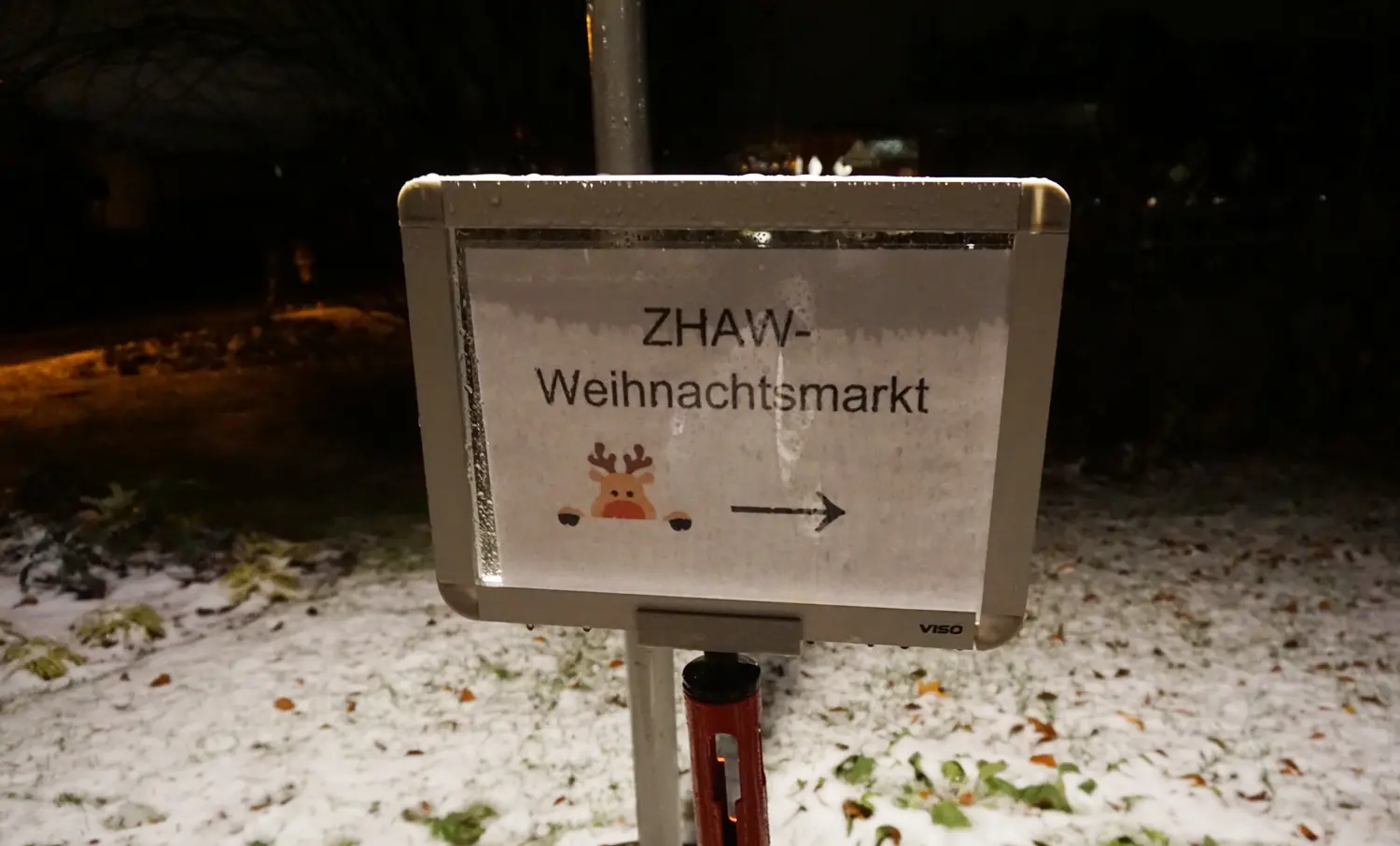 Ein Schild, das im Schnee steht und auf dem ZHAW-Weihnachtsmarkt steht.