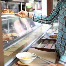 Woman taking plate with lunch in canteen