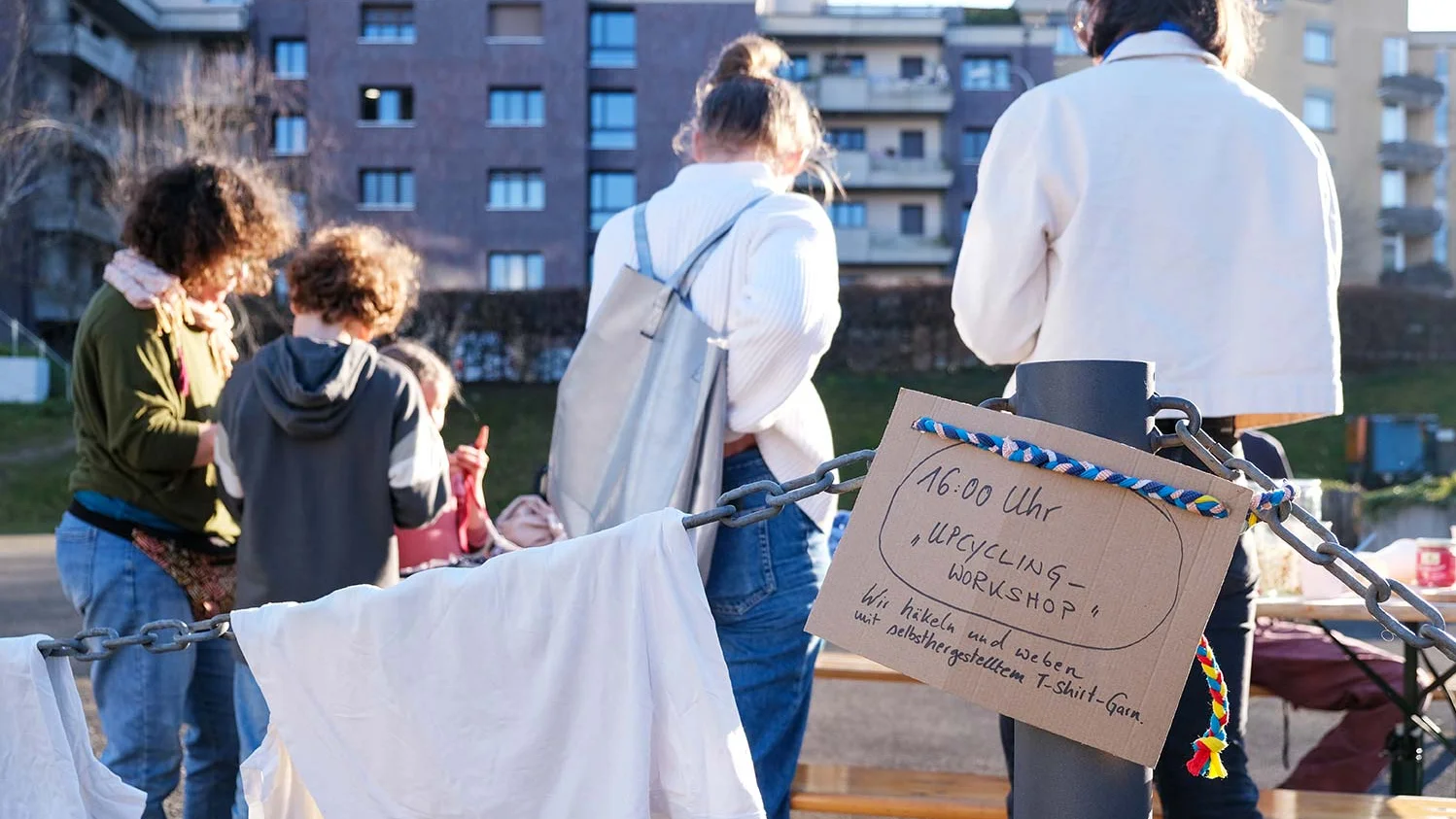 Ein Gruppe Menschen steht auf einem Flohmarkt und diskutiert miteinander.