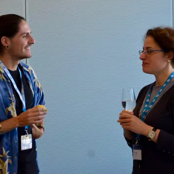 Konferenzbüro. Zwei Teilnehmende, stehend, unterhalten sich während der Kaffeepause.