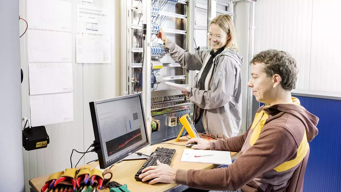 Mann und Frau führen Messungen durch und werten sie am Computer aus. 