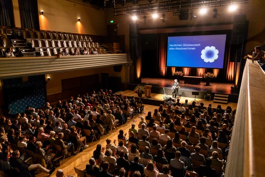 Bild vergrössern: Weitwinkel-Blick von der Empore in den fast vollbesetzten festlich beleuchteten Theatersaal.