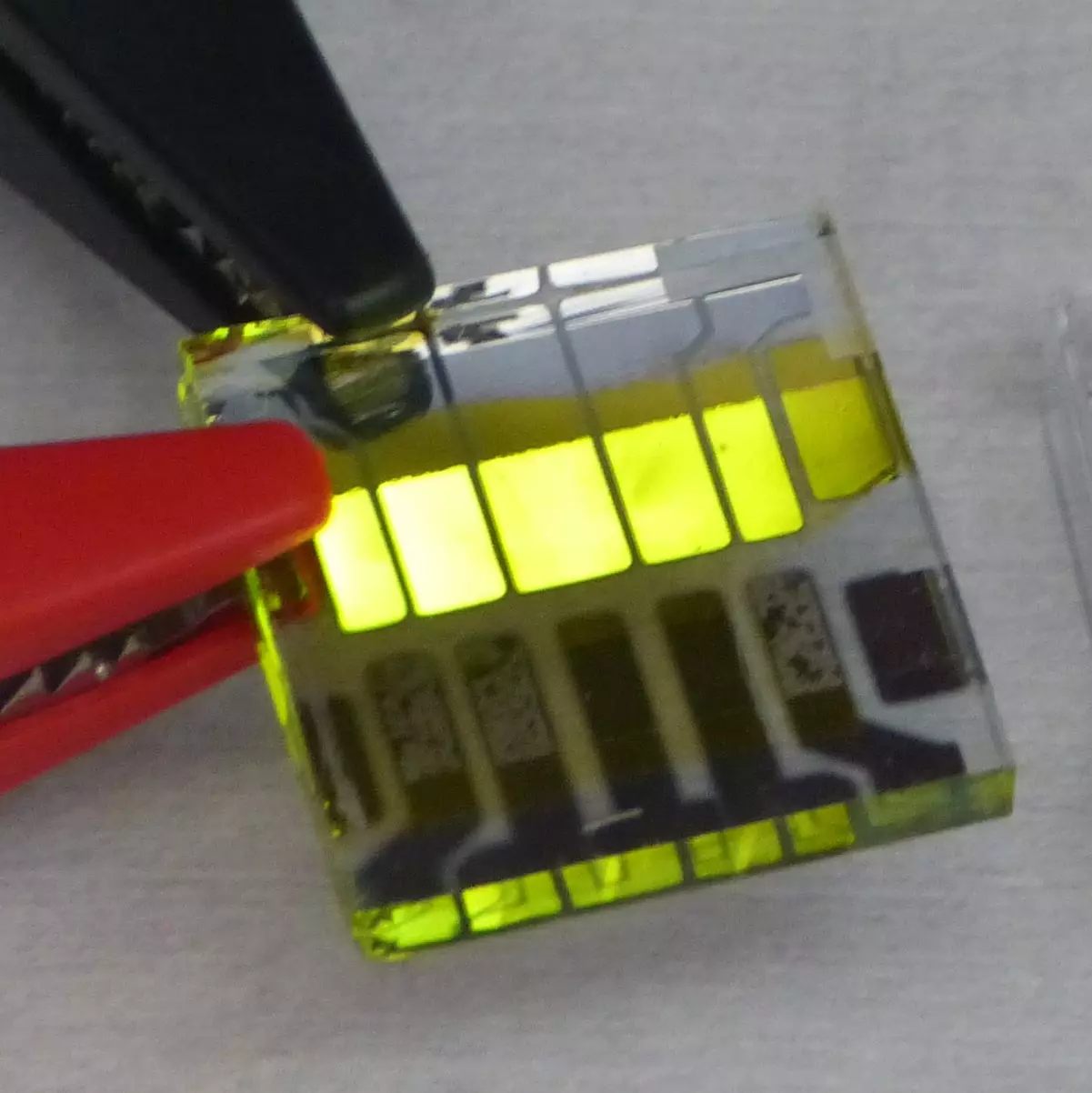 Das Bild zeigt ein Glas Substrat auf dem 5 OLEDs leuchten
