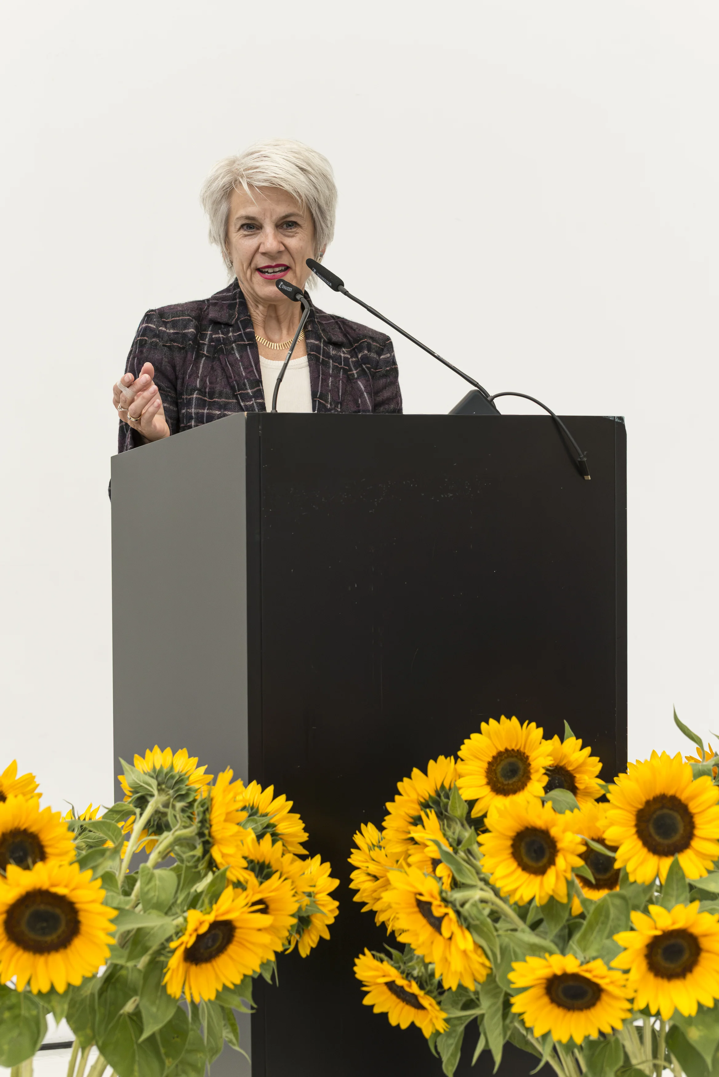 Rednerin am Pult mit Sonnenblumen bei der Diplomfeier 2026