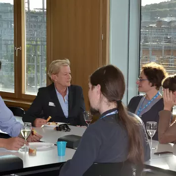 Apéro. Eine Gruppe von Konferenzteilnehmenden sitzt beim Apéro um einen Tisch.