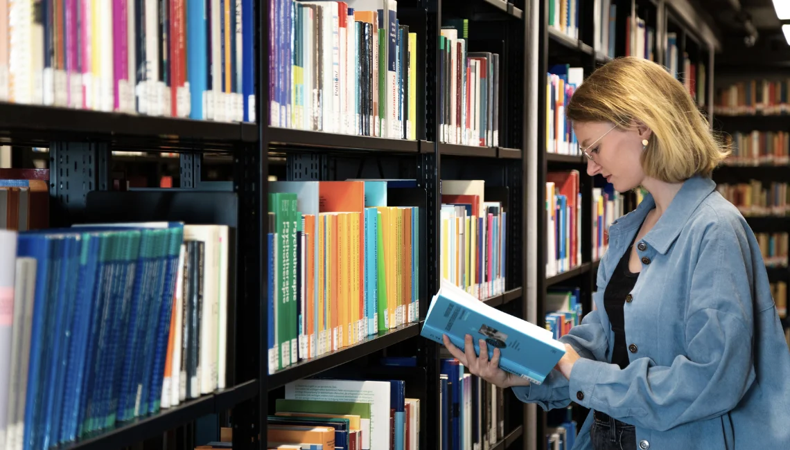 Studentin bei der Bücherauswahl in der Bibliothek