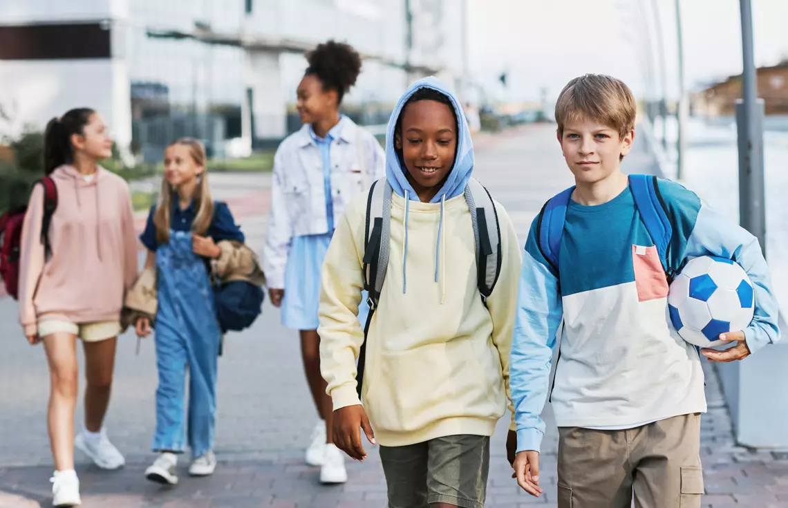 Group of intercultural adolescent secondary school learners in casualwear walking along street while going home after classes