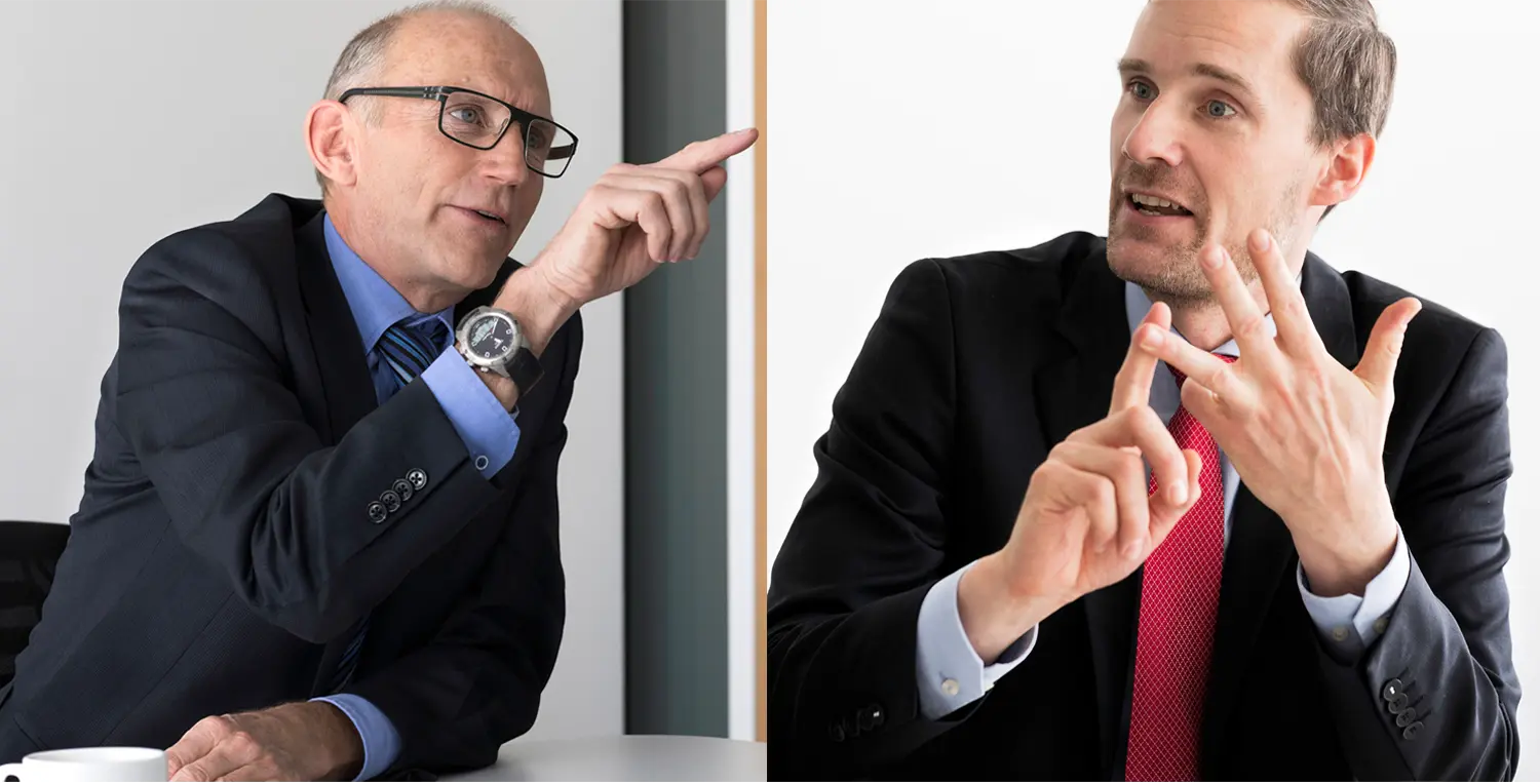 Andreas Burgener von Auto-Schweiz und ZHAW-Experte Thomas Sauter-Servaes sitzen am Tisch und führen ein hitziges Gespräch.