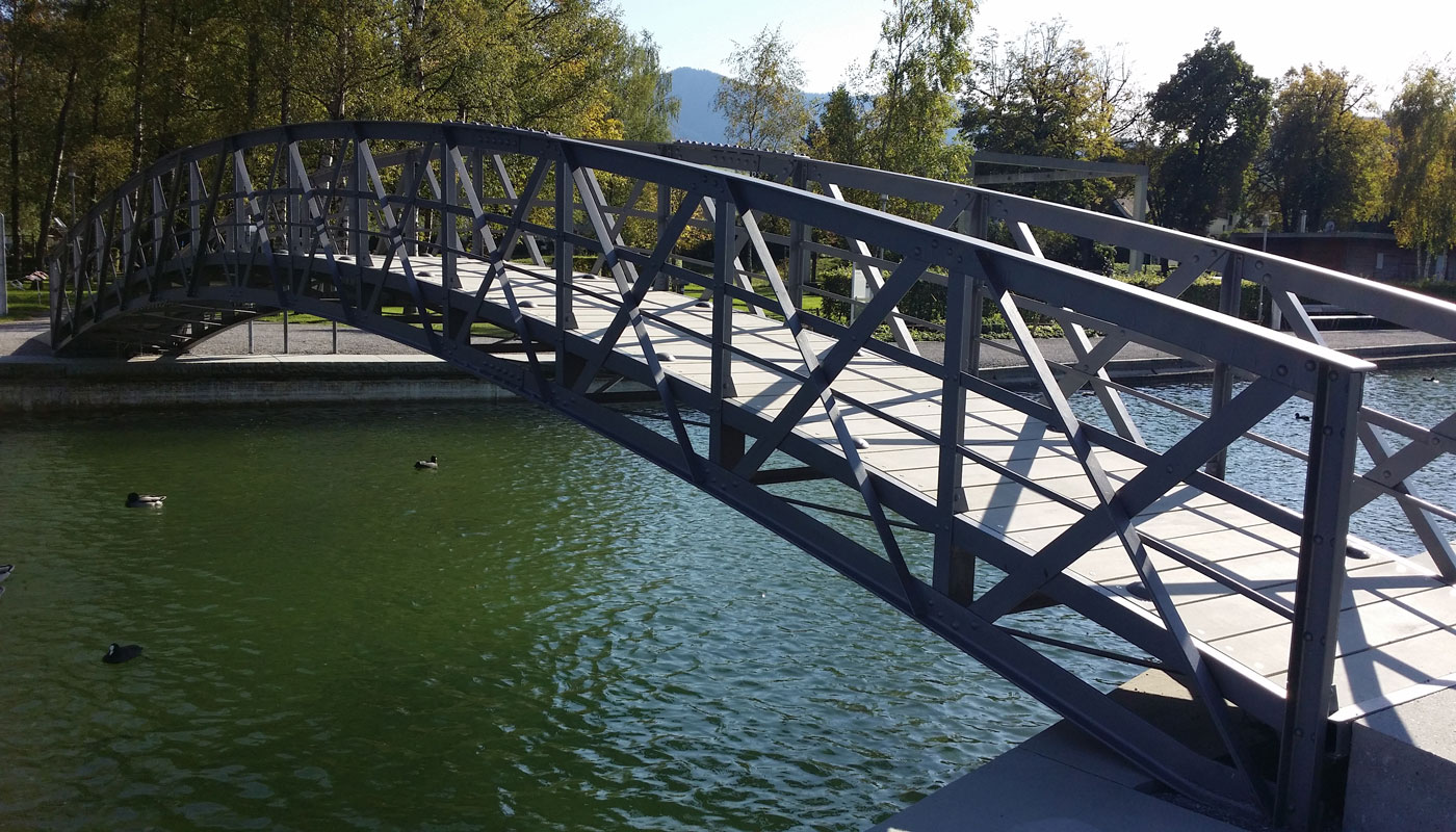 Uferpromenade Unterägeri
Die mehr als 100-jährige, denkmalgeschützte Stahlbrücke musste im Jahr 2013 umfassend instandgesetzt werden. Sie erhielt einen neuen Belag aus schlanken, kohlefaserbewehrten Betonbohlen, der die Auflast der Brücke reduziert.