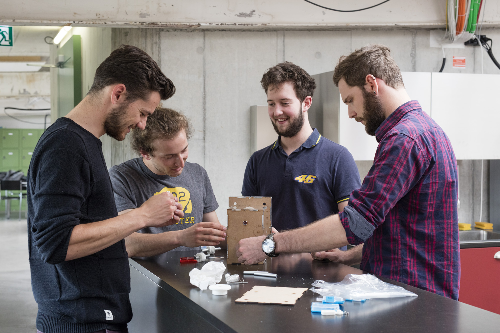 Vier Studenten tüfteln stehend an einem Prototypen für das neue Getriebe