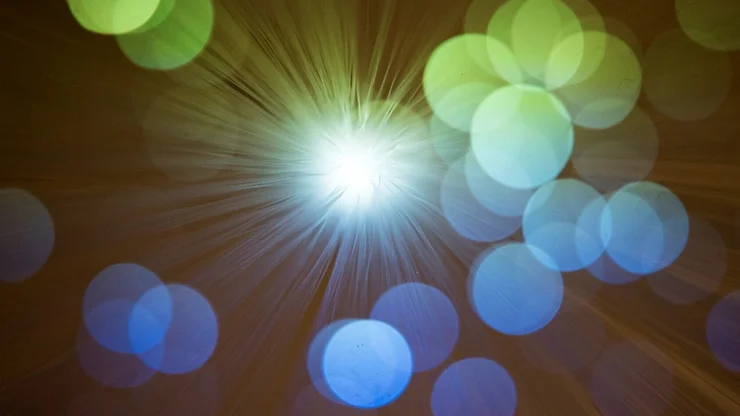 Eine Lichtquelle erhellt das Bild, im Vordergrund sieht man Kreise, die durch das Licht erhellt werden.