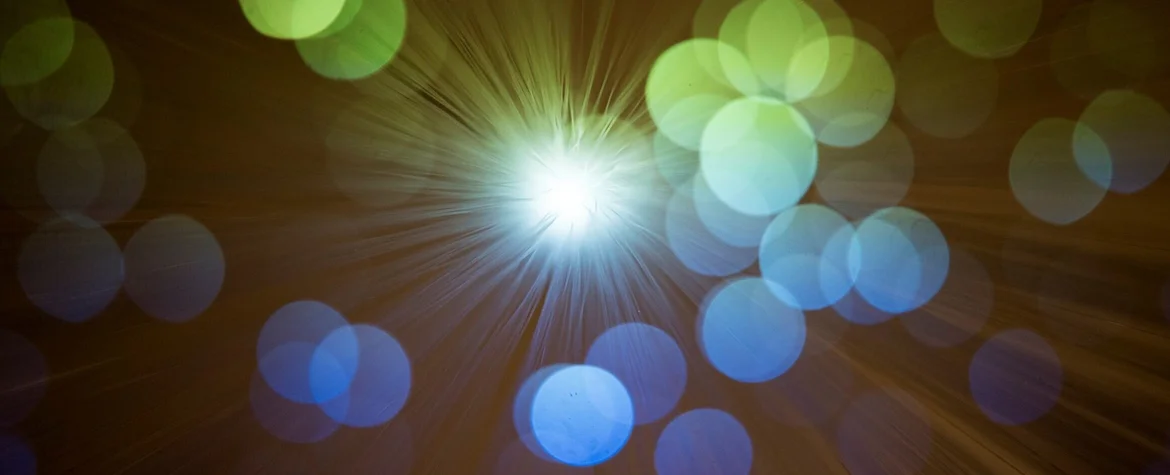 Eine Lichtquelle erhellt das Bild, im Vordergrund sieht man Kreise, die durch das Licht erhellt werden.