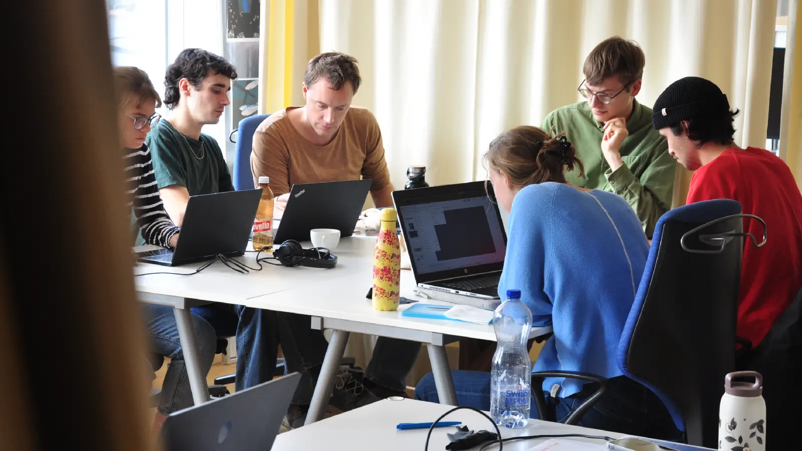 sechs Studierende sind mit Laptops in eine Gruppenarbeit vertieft