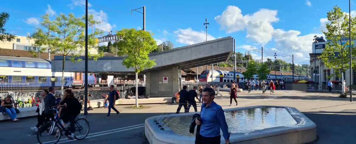 Smart City Winterthur Visual: Ein Platz neben dem Bahnhof in Winterthur mit einem Brunnen. Mehrere Personen schlendern über den Platz.