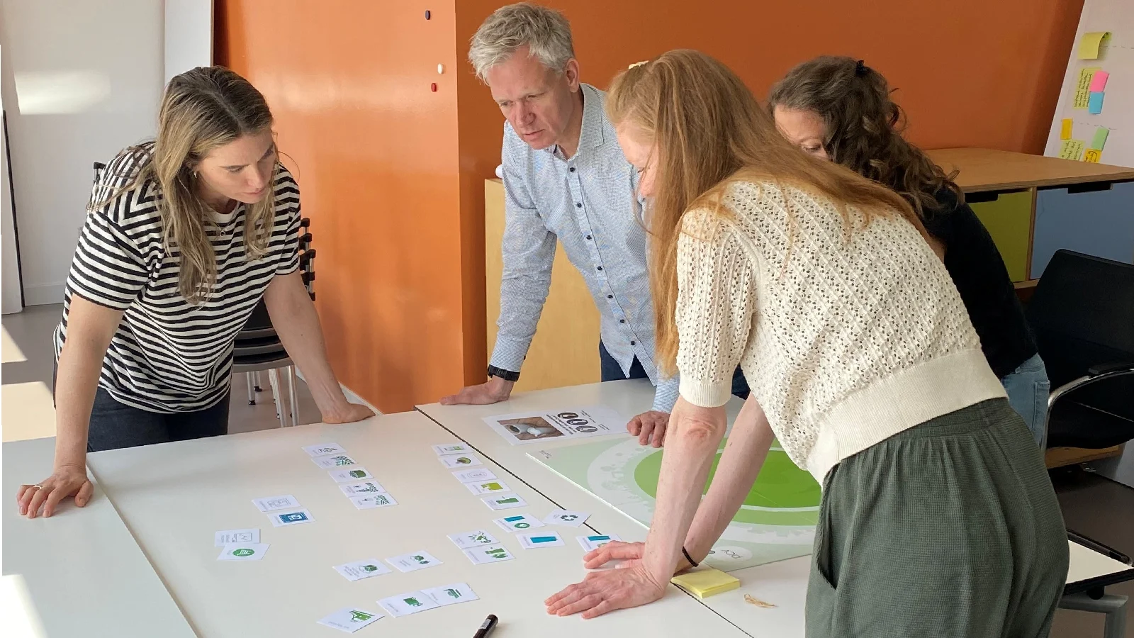 There are four people standing around a table, discussing sustainability.