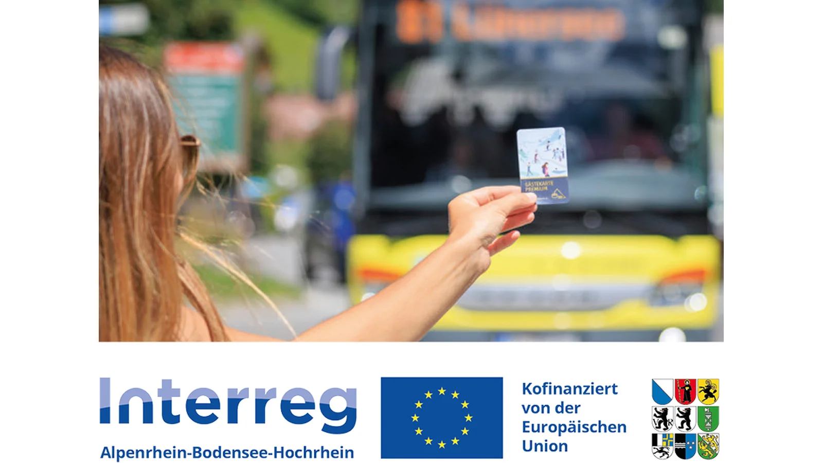 Ein Frau hält eine Fahrkarte mit der linken Hand ins Bild. Von hinten kommt ein Bus zur Haltestelle
