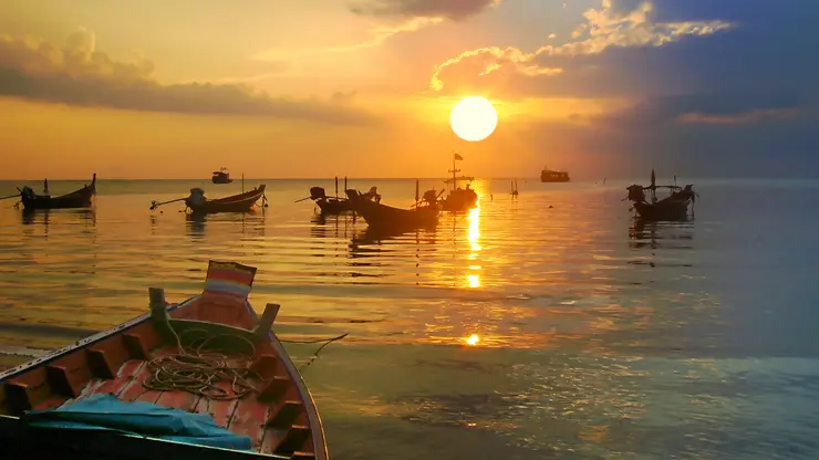 Picture of small thai boats on the sea at sunset.
