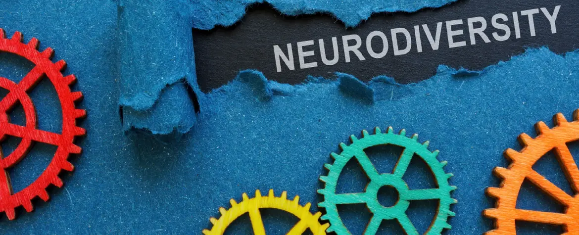 Verschiedenfarbige Zahräder auf blaueum Untergrund. Ein Riss im Untergrund und darauf steht in Grossbuchstaben "NEURODIVERSITY".