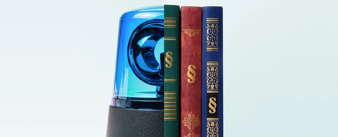 Eine blaue Polizei-Sirene steht neben drei juristischen Büchern.